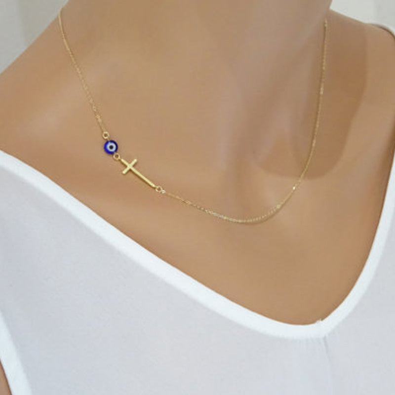 Dainty sideways cross necklace with a blue evil eye bead