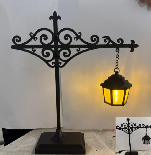 Mini black lantern lamp hanging from a scroll stand